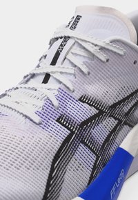 Κοντινό πλάνο λευκού αθλητικού παπουτσιού με μαύρο λογότυπο, λευκά κορδόνια, επάνω μέρος από δίχτυ και μπλε σόλα με την επιγραφή "FF Leap" στο πλάι.