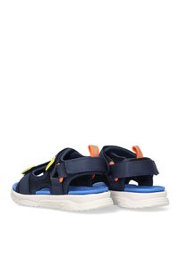 Sandalias azul marino con parte superior de malla, correas de Velcro y acentos en naranja y amarillo brillantes. Suela texturizada blanca con una plantilla azul.