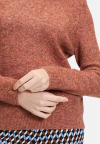 Rustfarbener Pullover aus weichem, strukturiertem Strick. Mit gerippten Bündchen und Saum, entspanntem Schnitt und leicht abgesenkten Schulternähten.