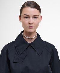 Czarna, kołnierzowa odzież wierzchnia o strukturalnym kształcie, z wyraźnym kołnierzem. Przyozdobiona perełkowym naszyjnikiem choker z złotymi akcentami.