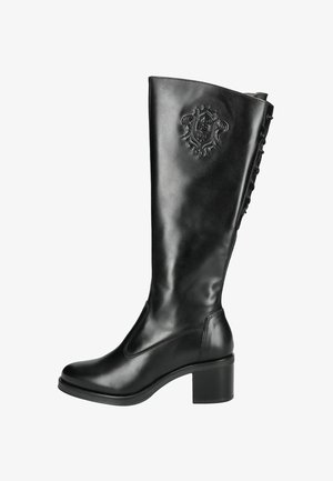 Botte en cuir noir, haute jusqu'au genou, avec un bout rond, un talon épais, un emblème en relief et des boucles décoratives sur le côté. Texture lisse et design élégant.