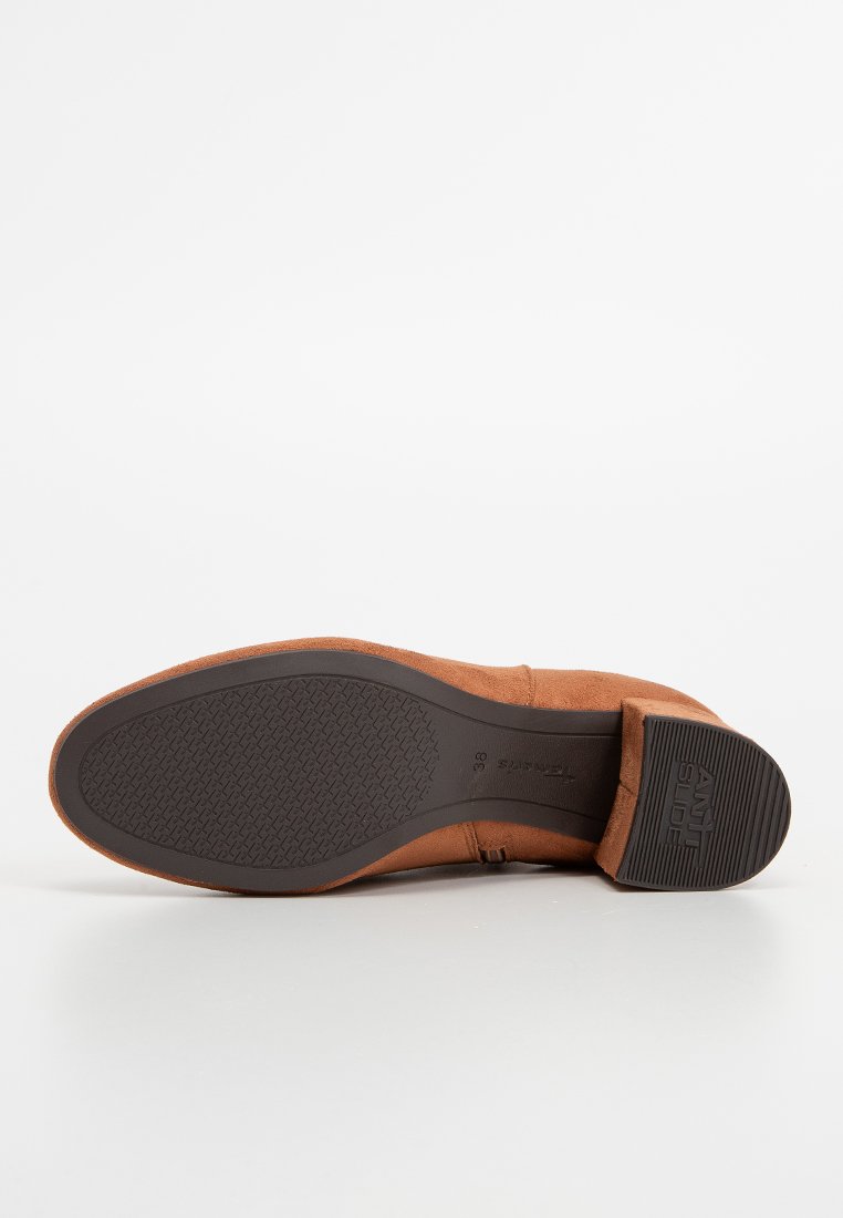Braune Wildleder-Stiefelette mit flacher Sohle, ausgestattet mit einer strukturierten Gummilaufsohle und einer genähten Verzierung an der Seite.