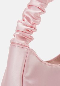 Sac à main en satin rose avec une poignée froncée, une texture lisse et une silhouette structurée. Couture visible le long des bords.