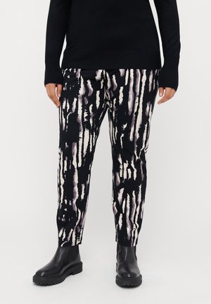 Zwart en crèmekleurige pants met een aquarelleffect, gekenmerkt door verticale strepen en een slim fit. Draagt een paar zwarte enkellaarsjes.