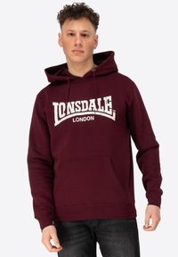 Maroon hoodie gemaakt van een katoenmix, met een voorzak, een capuchon met trekkoord en witte logo-tekst "Lonsdale London" in een gebogen ontwerp.