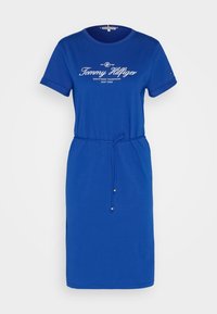 Robe t-shirt en coton bleu avec un col rond, des manches courtes et une taille à cordon. Présente le logo "Tommy Hilfiger" en blanc.
