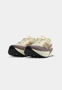 Beige and brown athletic shoes with a textured surface, lace-up design, and a black rubber outsole featuring a distinctive tread pattern.