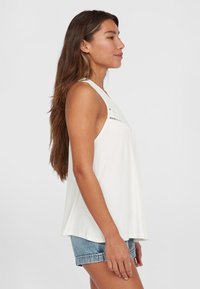 Top bianco senza maniche con scollatura rotonda, caratterizzato da delicati dettagli a taglio sul davanti. Abbinato a pantaloni corti in denim blu chiaro.