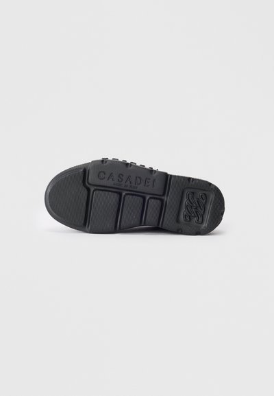 Zwarte rubberen zool van een schoen met het Casadei-logo en de tekst "Made in Italy" in reliëf in het midden van de zool.