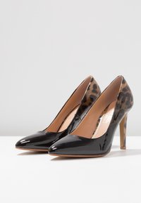 Escarpins en cuir verni noir avec un bout pointu, accents en imprimé léopard et un talon aiguille fin. Texture lisse, design élégant.