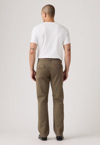 Καφέ βαμβακερό παντελόνι με ευθεία γραμμή, διαθέτει πίσω τσέπες και λεπτομέρειες ραφής, συνδυασμένο με εφαρμοστή λευκή κοντομάνικη μπλούζα.