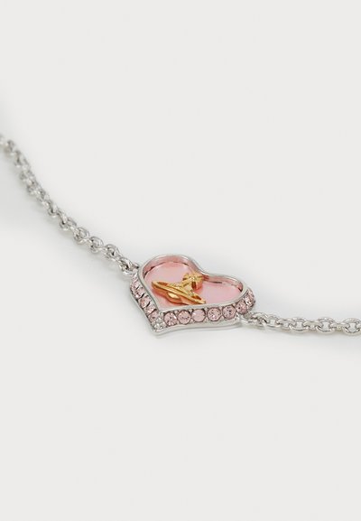Hjärtaformat armband med silverkedja, med en rosa emalj i mitten, guldaccent och kant av rosa rhinestones.