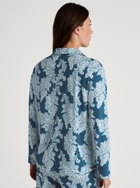 Mönstrad blus med långa ärmar i teal och vitt har en helhetsdesign med paisleymönster, krage och en mjuk tygkvalitet.