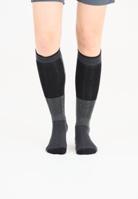 Knä-höga strumpor i olika nyanser av svart och grått, med ribbat mönster och släta detaljer. Mjuk material och åtsittande passform.