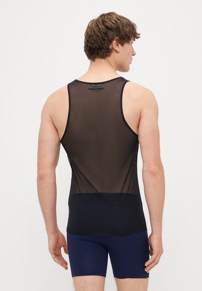 Fekete áttetsző trikó, alján sötét színű csíkkal, átlátszó anyagból; sötétkék sorttal viselve, hátulról nézve.