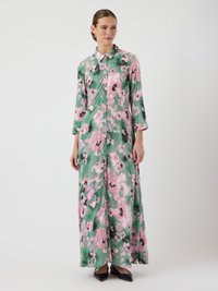 Robe maxi en tissu léger, avec une base verte ornée de grands motifs floraux roses, devant boutonné et manches trois-quarts.