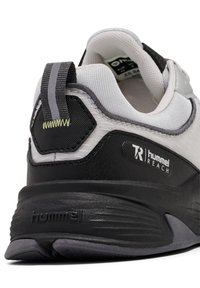 Scarpa sportiva nera e grigia con una parte superiore testurizzata, linguetta e logo prominente. Presenta una suola ammortizzata e cuciture a contrasto.