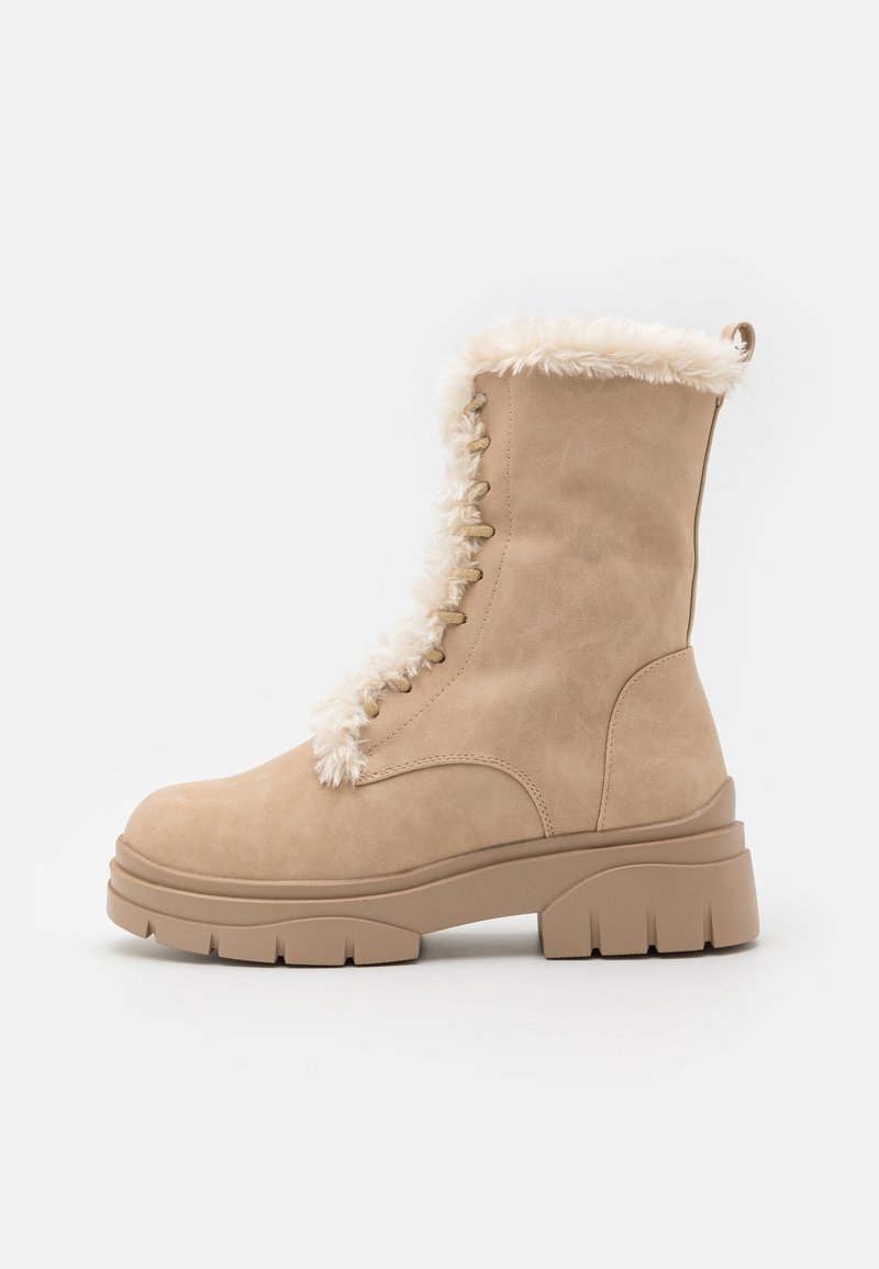 Bottine beige à semelle épaisse, lacets sur le devant et doublure en fourrure blanche et duveteuse le long de l'ouverture et de la languette, idéale pour l'hiver.