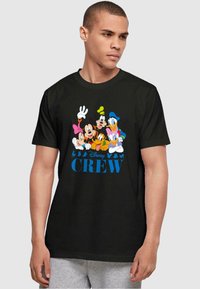 Camiseta negra con un gráfico colorido de personajes de Disney y el texto "Disney CREW" en azul. Mangas cortas con un diseño clásico de cuello redondo.