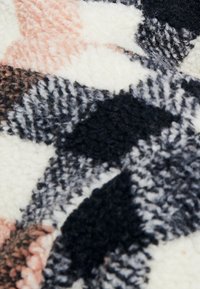 Texturovaná látka v krémové, černé, růžové a šedé barvě, s geometrickým vzorem a huňatými vlákny a výraznými tvary.