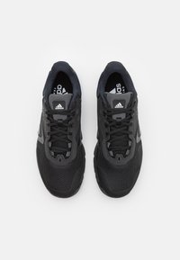 Black athletic sneakers featuring a mesh upper, tonal accents, and a rubber sole. Laces are secured through reinforced eyelets.
