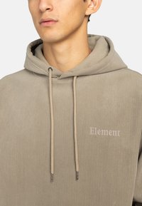 Sudadera de pana beige con cordón y logo bordado "Element". Textura suave y detalles de diseño acanalados.