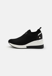 Scarpe sportive in maglia nera con suola a cuneo bianco e nero, dotate di un taschino sul tallone e una morbida accentuazione laterale a contrasto.