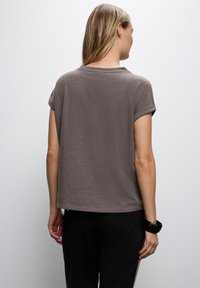 Brun kortärmad T-shirt med avslappnad passform, med rullade ärmslut och rundad halsringning. Snygg textur, avslappnad design.