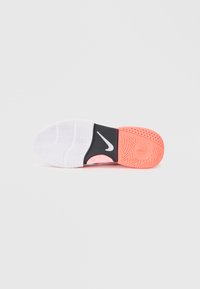 Nike shoe sole featuring rubber material, white and coral colors, textured patterns, with a pronounced Nike logo in white on a black section.