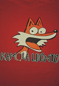 Červené tričko s kreslenou grafikou lišky s přehnanými obličejovými rysy. Pod tímto je napsáno "KAMALA LUONTO" černobílými písmeny.