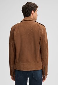 Bruine suede jas met een vlakke kraag, schuine schouderepauletten en ritsmanchetten. Gladde textuur, getailleerde pasvorm. Achteraanzicht weergegeven.