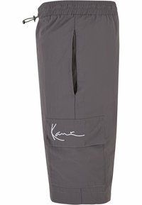 Shorts gris fabriqués en tissu léger, avec une taille élastique, une poche latérale et un logo blanc brodé bien visible.