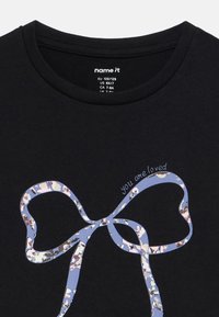 Czarna koszulka z grafiką błękitnej wstążki ze wzorem kwiatowym oraz napisem "you are loved" w stylu kursywy.