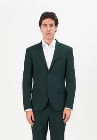 Dark green suit with single-breasted jacket, two buttons, notch lapels, and chest pocket. White shirt underneath, smooth texture.