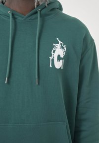 Dark green hoodie featuring a front pocket, drawstring hood, and a white graphic design with figures and a letter "C" on the chest.