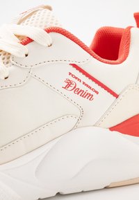 Valkoiset lenkkarit punaisilla yksityiskohdilla, verkkokangasta, tekstuurilla varustettu kumipohja ja "Tom Tailor Denim" -logo. Tasainen pinta ja ommeltu yksityiskohtia.