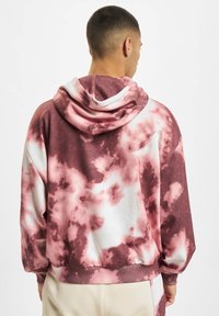Felpa con cappuccio tie-dye caratterizzata da motivi in rosa tenue e bianco. Realizzata in un tessuto morbido con una vestibilità comoda e un cappuccio con coulisse.