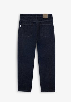 Jeans en denim bleu foncé avec une coupe droite, dotés de deux poches arrière et d'un patch en cuir avec la marque au niveau de la taille. Tissu texturé.