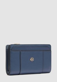 Portafoglio in pelle blu con pannelli cuciti, piccolo logo metallico sul davanti e scomparto con cerniera sulla parte superiore.