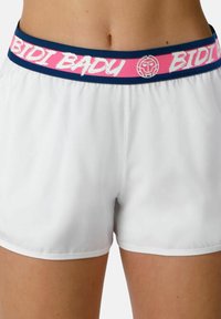 Pantalones cortos atléticos blancos con una cinturilla elástica en rosa y azul marino que presenta el logo "BIDI BADU" y un emblema de cara estilizada.