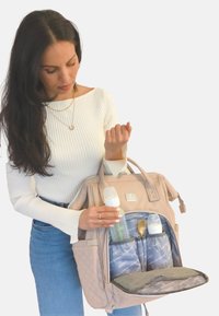 Bolsa para pañales de color beige con textura acolchada, bolsillo delantero que muestra dos biberones y una cuchara. En el interior presenta un forro gris con estampado y compartimentos.