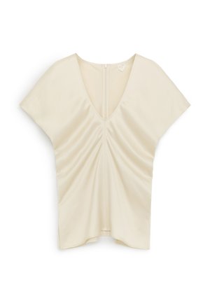 Crèmekleurige blouse met korte mouwen, V-hals, geplooide voorkant en ritssluiting aan de achterkant, weergegeven op een witte achtergrond.