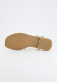 Beige sandaler med jevn overflate, justerbar spenne og preget merkevarelogo på sålen. Flat, lett design for komfort.