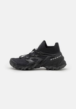 Sort Mammut trail løbesko med robust sål, elastisk anklerem og hurtigt snøresystem på hvid baggrund.