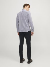 Gestreiftes Langarmhemd in Blau und Weiß, taillierte Passform, mit klassischem Kragen und knöpfbaren Manschetten. Getragen mit dunklen Hosen und Schuhen.