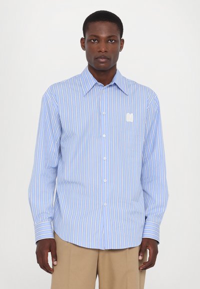 Camisa de manga larga azul claro con rayas verticales en blanco y marino, cierre de botones y un pequeño detalle bordado en el bolsillo izquierdo del pecho.