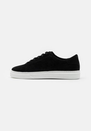 Czarny niski sneaker z cholewką z zamszu, czarnymi sznurowadłami i białą gumową podeszwą, pokazany z boku na białym tle.