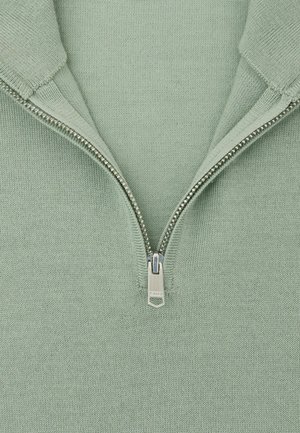 Pull à fermeture éclair vert clair en maille texturée, avec un col court et une fermeture éclair métallique équipée d'un curseur rectangulaire.