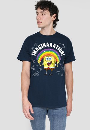 Navyblaue Baumwoll-T-Shirt mit einem gelben Cartoon-Charakter, der einen Regenbogen hält, und weißem Text "IMAGINAATION!" sowie floralen Akzenten.