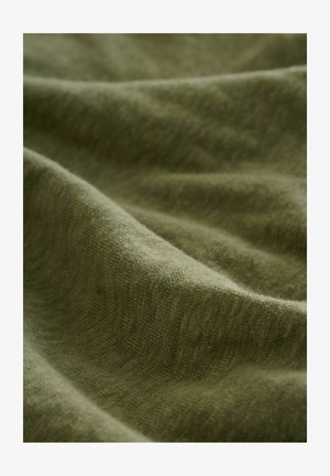 Olíva zöld szövet, amelynek puha, texturált felülete van. Az anyag finom árnyalatváltozásokat mutat, amely lágy redőket és kontúrokat hoz létre.